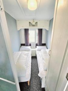 a small room with two beds and a window at Golden Anchor 8b9 Caravan Park Holiday Home in Chapel Saint Leonards