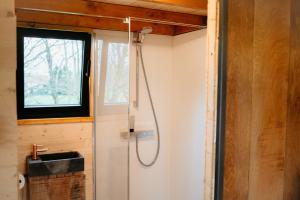 La salle de bains est pourvue d'une douche et d'une fenêtre. dans l'établissement Berta Tiny house, à Verlaine