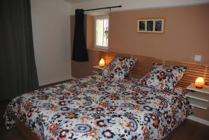 een slaapkamer met een bed met een bloemdekbed en 2 lampen bij Appartement cosy au deuxième étage in Malaucène
