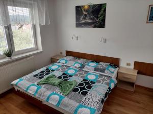 a bedroom with a bed with a quilt on it at Penzion MAYKA in Hrabušice