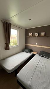 two beds in a room with a window at Mobilhome cosy tout confort 6-8 personnes in Valras-Plage
