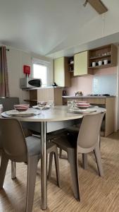 a kitchen with a table and chairs in a room at Mobilhome cosy tout confort 6-8 personnes in Valras-Plage