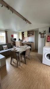 a kitchen and living room with a table and a laundry at Mobilhome cosy tout confort 6-8 personnes in Valras-Plage