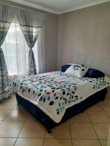 a bedroom with a bed with a blue and white comforter at Comfort at its Best! in Brits