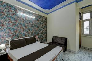 um quarto com uma cama e uma cadeira em OYO Flagship HOTEL RAJENDRA PALACE em Kanpur