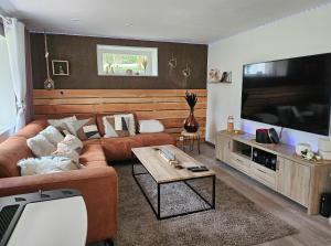 uma sala de estar com um sofá e uma televisão de ecrã plano em la perle blanche em Spa