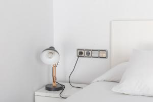 a lamp on a nightstand next to a bed at Mazi Apartments Colón in Vic