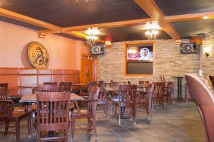 un ristorante con tavoli e sedie in legno e una TV di Twin Pine Inn & Suites a Hinton
