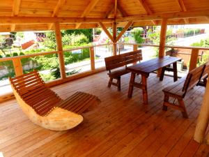 una terraza de madera con bancos, mesa y sillas en Noclegi Relax, en Ruciane-Nida