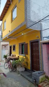 a yellow house with a bike parked in front of it at Hospedagem do Neto in Saquarema