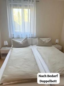 uma grande cama branca num quarto com uma janela em La Pura Vida em Bühlertann