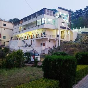ein großes weißes Haus auf einem Hügel in der Unterkunft Hotel Tribhuvan Ranikhet Near Mall Road - Mountain View -Parking Facilities - Excellent Customer Service Awarded - Best Seller in Rānīkhet