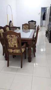 - une table à manger et des chaises sur un sol blanc dans l'établissement KJ HOMESTAY SUNGAI PETANI, à Sungai Petani