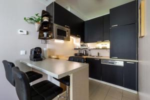 a kitchen with black cabinets and a counter with chairs at Apartment with garden close to Stadthalle, Westbahnhof in Vienna +16 photos