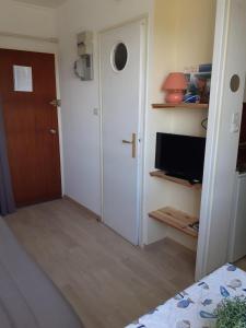 Zimmer mit einer Tür, einem TV und einem Schlafzimmer in der Unterkunft Studio - Marina 6 - 37 allée des pinons - 3-1 in Saint-Jean-de-Monts