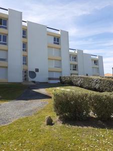 a large white building with bushes in front of it at Studio - Marina 6 - 37 allée des pinons - 3-1 in Saint-Jean-de-Monts