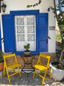 duas cadeiras amarelas e uma mesa em frente a uma janela em Zoe’s & Patty’s Guest House em Galaxidi