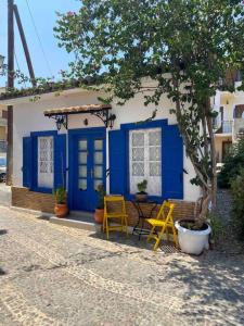 uma pequena casa com portas azuis e cadeiras amarelas em Zoe’s & Patty’s Guest House em Galaxidi
