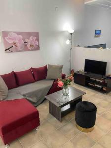 a living room with a red couch and a table at Zoe’s & Patty’s Guest House in Galaxidhion