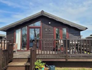 a small wooden cabin with a porch and a deck at Stunning 2 Bed Lodge On The Lake in South Cerney