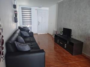 sala de estar con sofá negro y TV en Lo más cómodo en San Diego. en San Diego