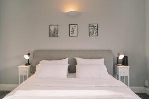 a bedroom with a large white bed with two night stands at Modern Flat by the Underground. in London