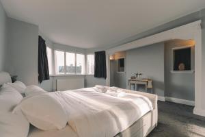a bedroom with a large white bed with white pillows at Modern Flat by the Underground. in London