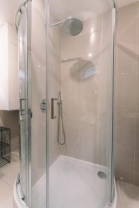 a shower with a glass door in a bathroom at Modern Flat by the Underground. in London