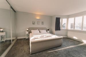 a white bedroom with a bed and windows at Modern Flat by the Underground. in London