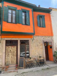 een oranje gebouw met tafels en stoelen ervoor bij Ayvalık'taki Eviniz in Ayvalık