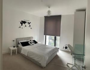 a white bedroom with a bed and a window at Perfect flat next to Wembley Stadium in London
