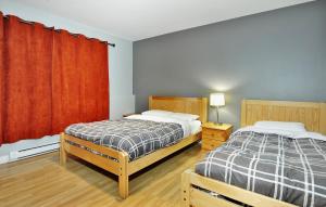 1 dormitorio con 2 camas y cortina roja en Chalets Alpins- 15 Chemin des Skieurs, en Stoneham