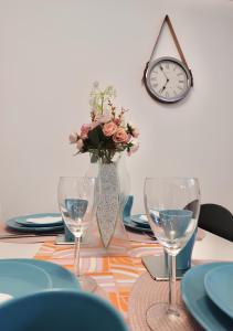 a table with two wine glasses and a vase with flowers at Helsinki Seaside Home with Free Parking in Helsinki