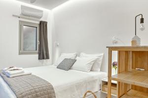 a white bedroom with a bed and a wooden table at Kumquart estate- Kumquat in Aspiotádes