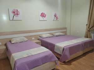 two beds in a room with purple sheets at Apartment Eclipse in Sarandë