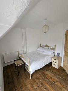 1 dormitorio blanco con 1 cama y 1 silla en Station Cottage en Haddiscoe