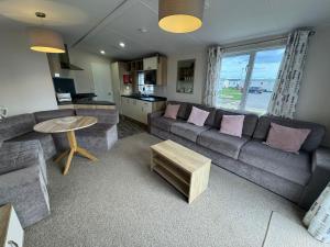 sala de estar con sofá y mesa en Golden Palm Resort - The Twilight - Coastal Caravan Breaks, en Chapel St. Leonards