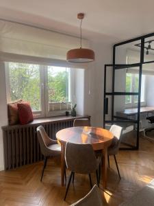 d'un salon avec une table, des chaises et une fenêtre. dans l'établissement Joli Apartment, à Varsovie