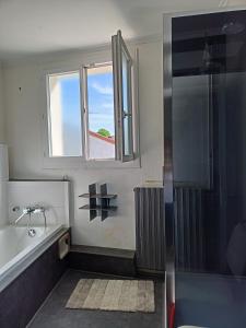 een badkamer met een bad, een wastafel en een raam bij Gîte du RELAI du Château - Parc Oriental - Puy du Fou in La Tourlandry