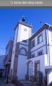 un grand bâtiment blanc avec une tour d'horloge dans l'établissement Sobre la villa 12, à Neda