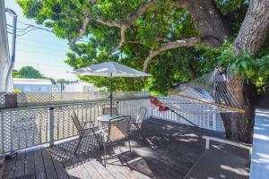a hammock and chairs on a deck with a tree at Traveler's Palm by Brightwild in Key West
