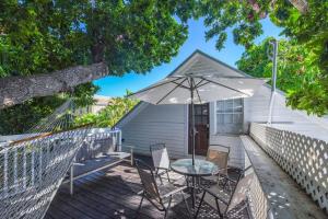 um pátio com uma mesa, cadeiras e um guarda-sol em Traveler's Palm by Brightwild em Key West