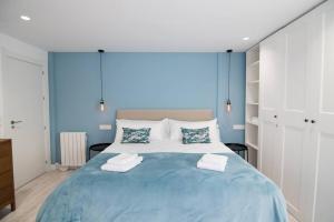 a blue bedroom with a large bed with towels on it at Amplio y moderno apartamento en el centro de Graná in Granada