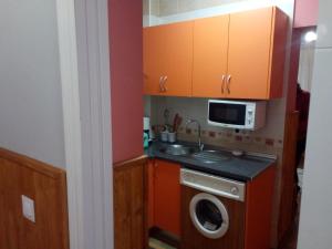 a kitchen with a washing machine and a microwave at Apartamento araceli in Chipiona