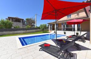 a pool with a red umbrella and two chairs and a table with a red umbrella at Ferienhaus mit Privatpool für 8 Personen ca 130 qm in Divšići, Istrien Südküste von Istrien in Divšići