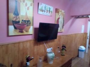 TV en una pared en una habitación con paredes rosas en Apartamento araceli en Chipiona