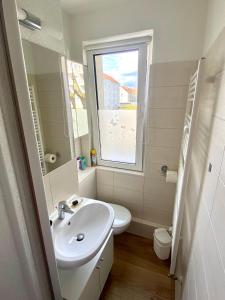 een witte badkamer met een wastafel en een raam bij Komplette Wohnung nahe am See in Prenzlau