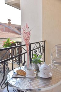 Villa Marto Old Town Ohrid في أوخريد: طاولة زجاجية مع أكواب الشاي و مزهرية مع الزهور