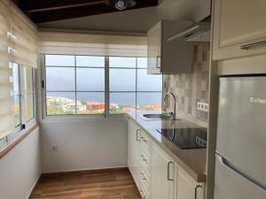 Una cocina con gabinetes blancos y una ventana grande. en Vivienda Vacacional Los Frailes 2, en Breña Baja