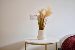 a white vase with a plant on a table at Cherish Stays spacious & amazing 3 Bed House in Hayes & Heathrow in West Drayton